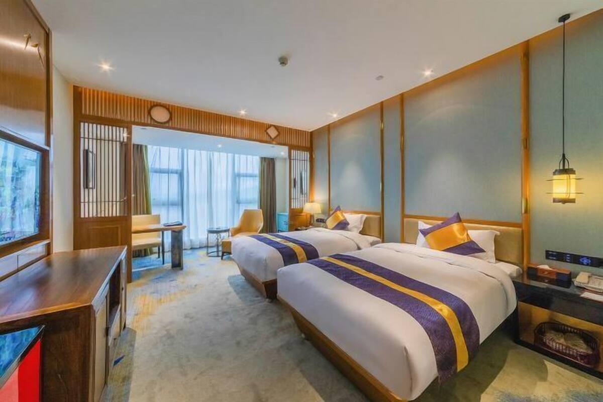 Une chambre d’hôtel avec deux lits, un bureau et une chaise.