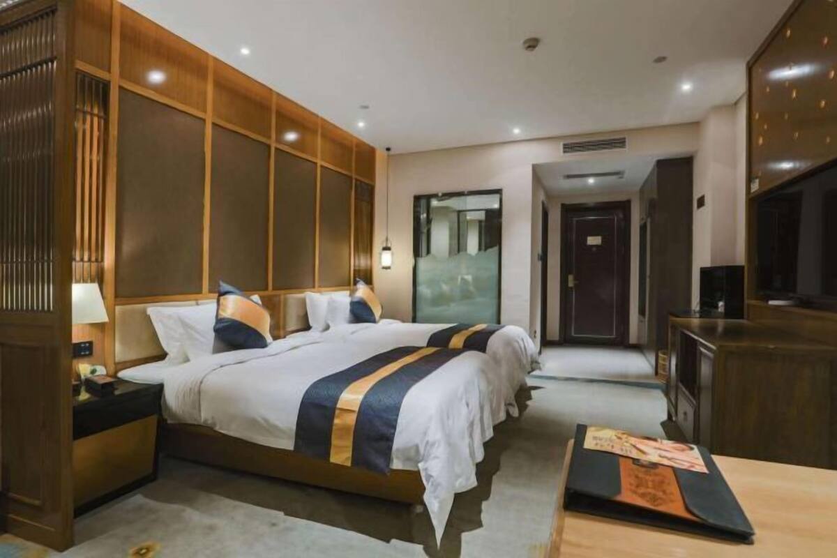 Une chambre d’hôtel avec deux lits, un bureau, une télévision et un grand miroir.
