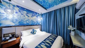 Et hotelværelse med en seng, et natbord, et skrivebord og en væg med et blåt abstrakt design.