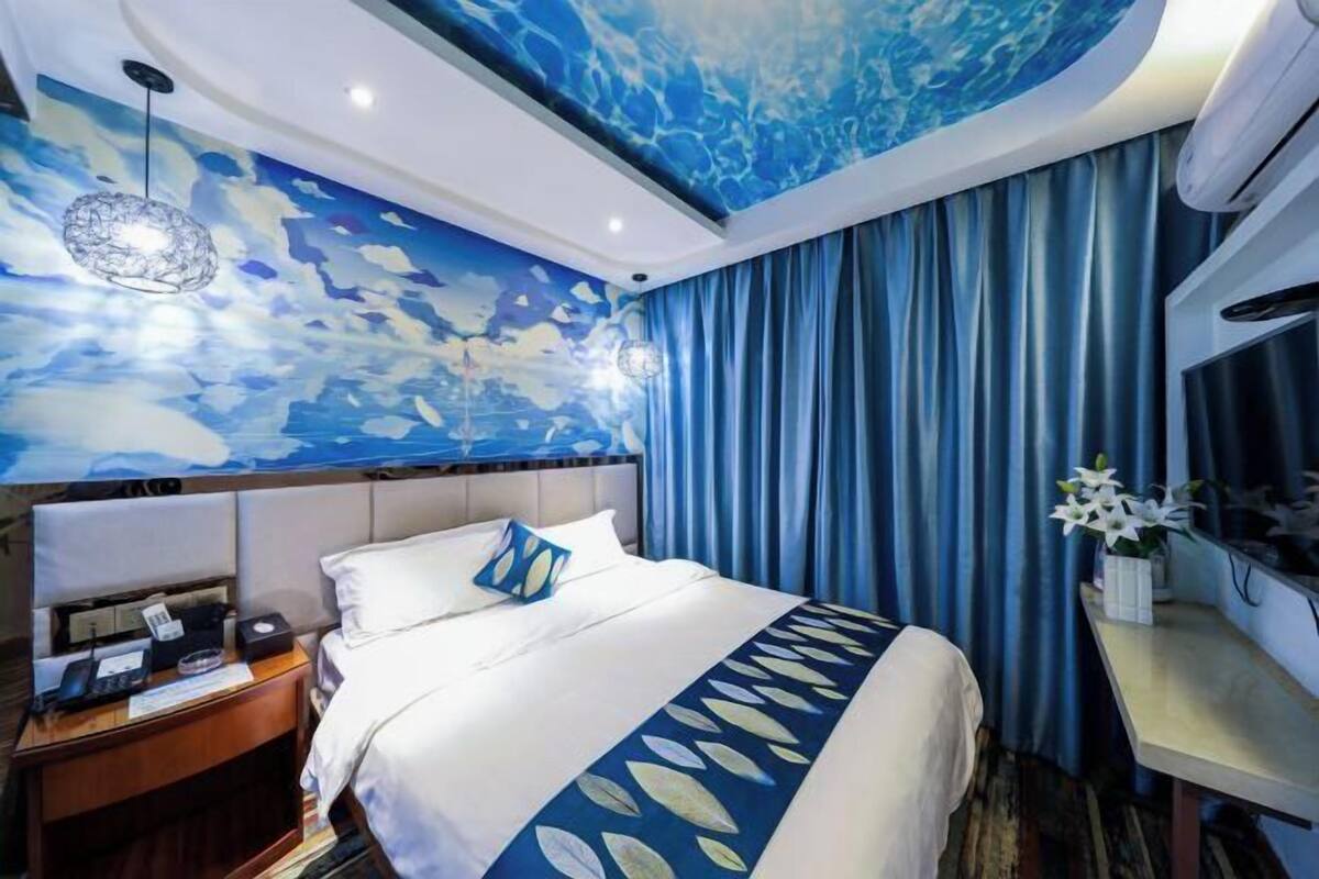 Una habitación de hotel con una cama, una mesita de noche, un escritorio y una pared con un diseño abstracto azul.