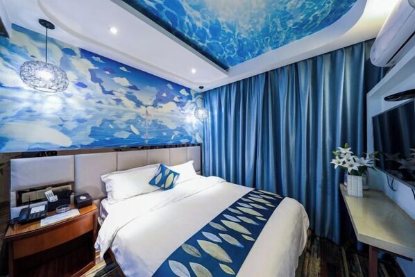 Una habitación de hotel con una cama, una mesita de noche, un escritorio y una pared con un diseño abstracto azul.