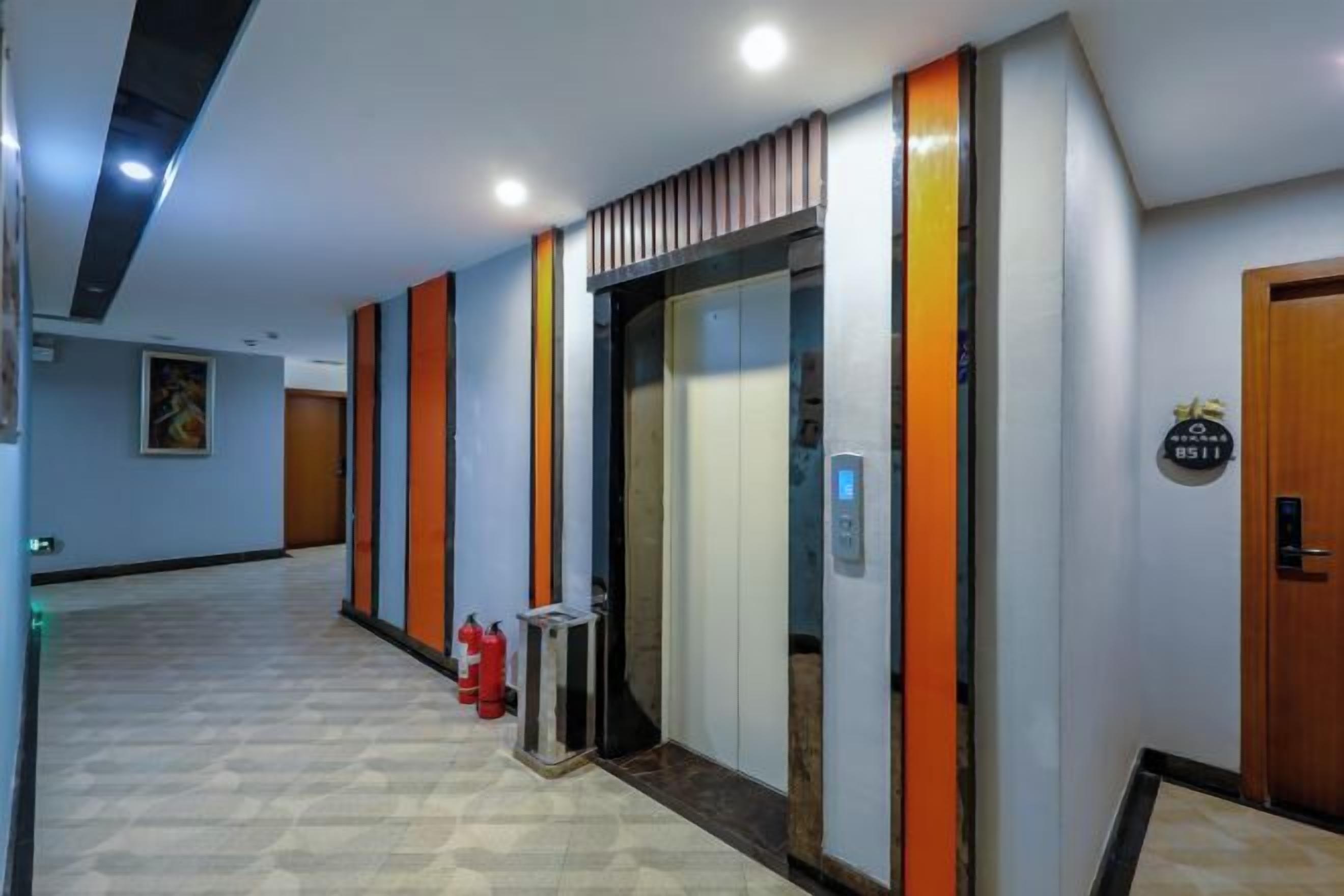 Un pasillo de hotel con un ascensor, un extintor y una puerta con un letrero.