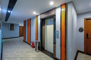 Un pasillo de hotel con un ascensor, un extintor y una puerta con un letrero.