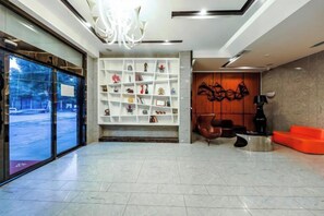 A lobby with a reception desk, a seating area, and a decorative wall. - Orange Fashion Hotel (Shaoyang College Road Store) (Shaoyang)
