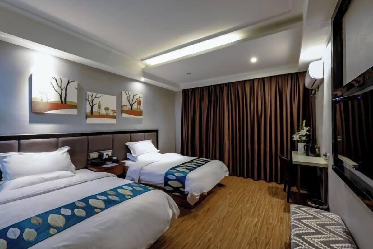 Habitación de hotel con dos camas, un escritorio, una silla y un televisor.