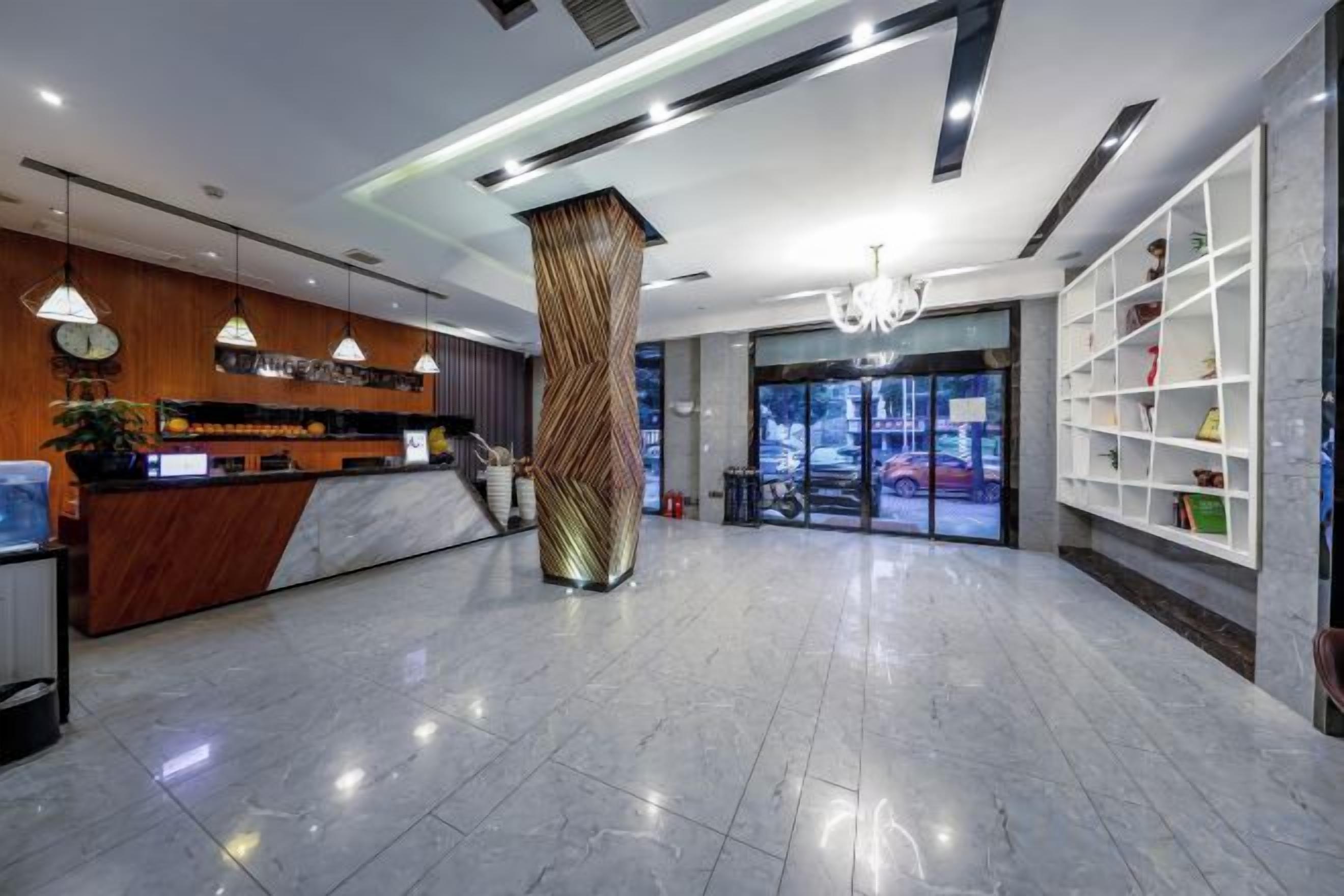 A hotel lobby with a reception desk, a large pillar, and a view of the outside.