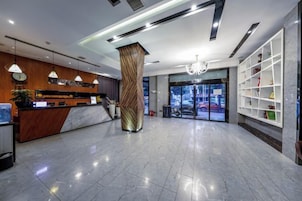 Un hall de hotel con una recepción, un pilar grande y vistas al exterior.