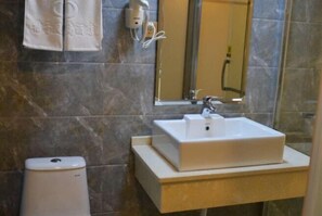 A bathroom with a white sink, a mirror, and a towel hanging on the wall.