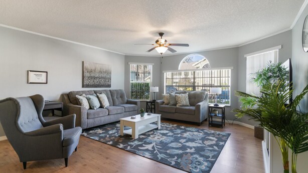 A spacious living room with two grey sofas, a white coffee table, and a large window providing natural light. - Villas at Island Club Community, Pools, Jacuzzi and More! (Kissimmee)