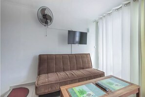 Relax in this cozy living space with a sofa, flat-screen TV, and ceiling fan.