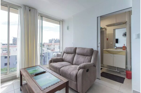 Relax in this stylish living room with a sofa, coffee table, and city views through large windows.