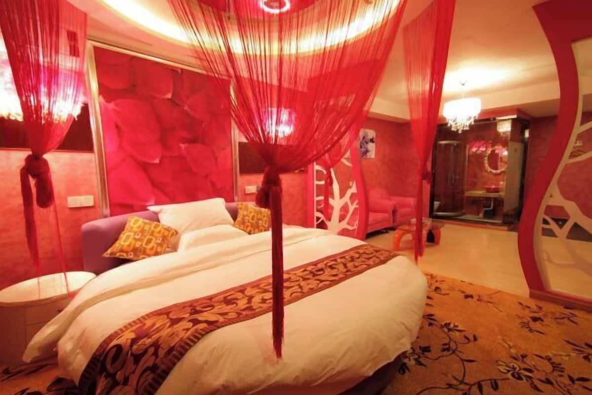 A bedroom with a bed, a nightstand, and a red canopy.
