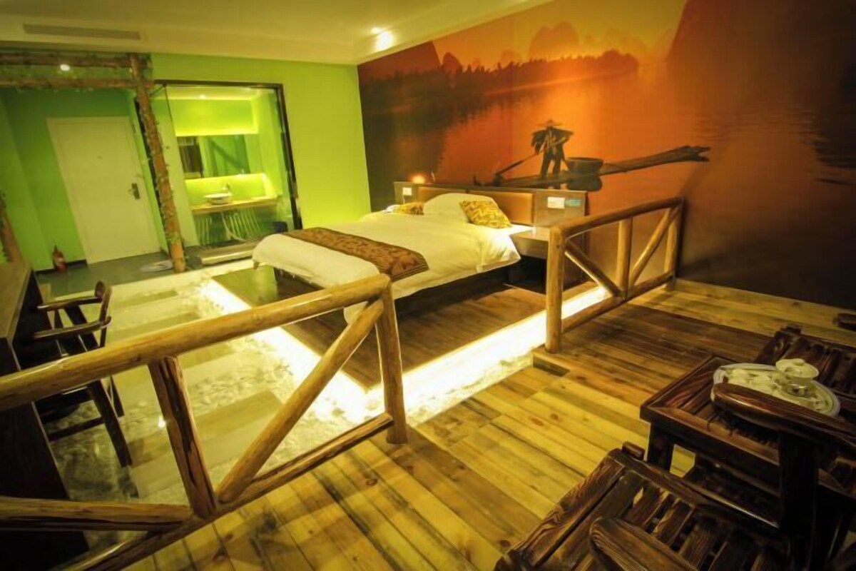 A room with a bed, wooden furniture, and a mural of a landscape.