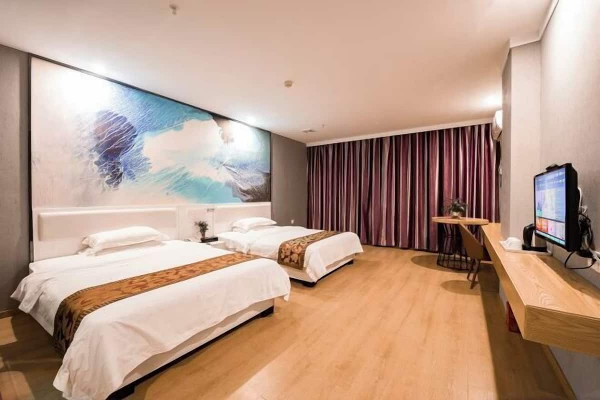 A hotel room with two beds, a large abstract painting on the wall, a TV, and a wooden desk.