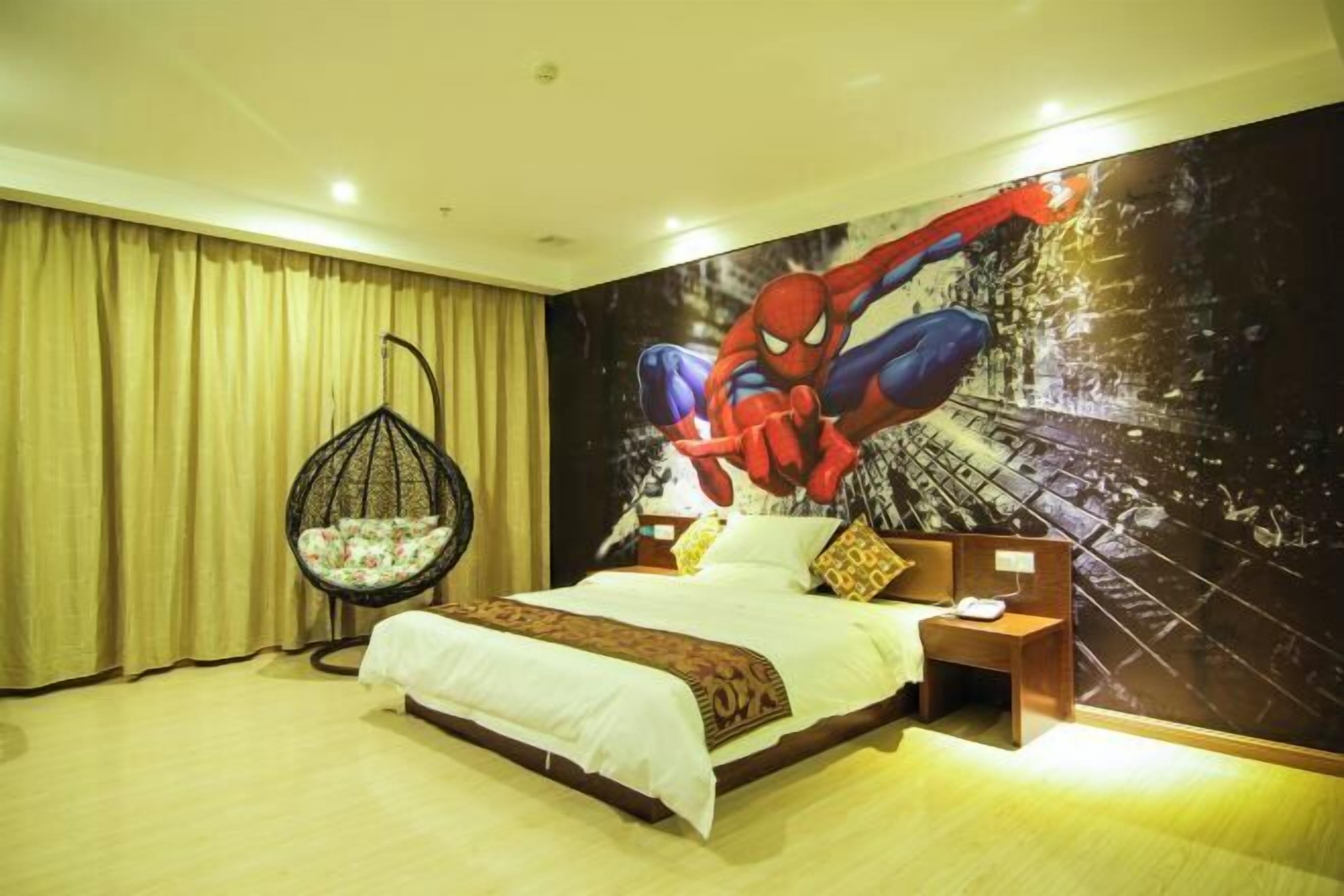 A bedroom with a large bed, a hanging chair, and a Spiderman mural on the wall.