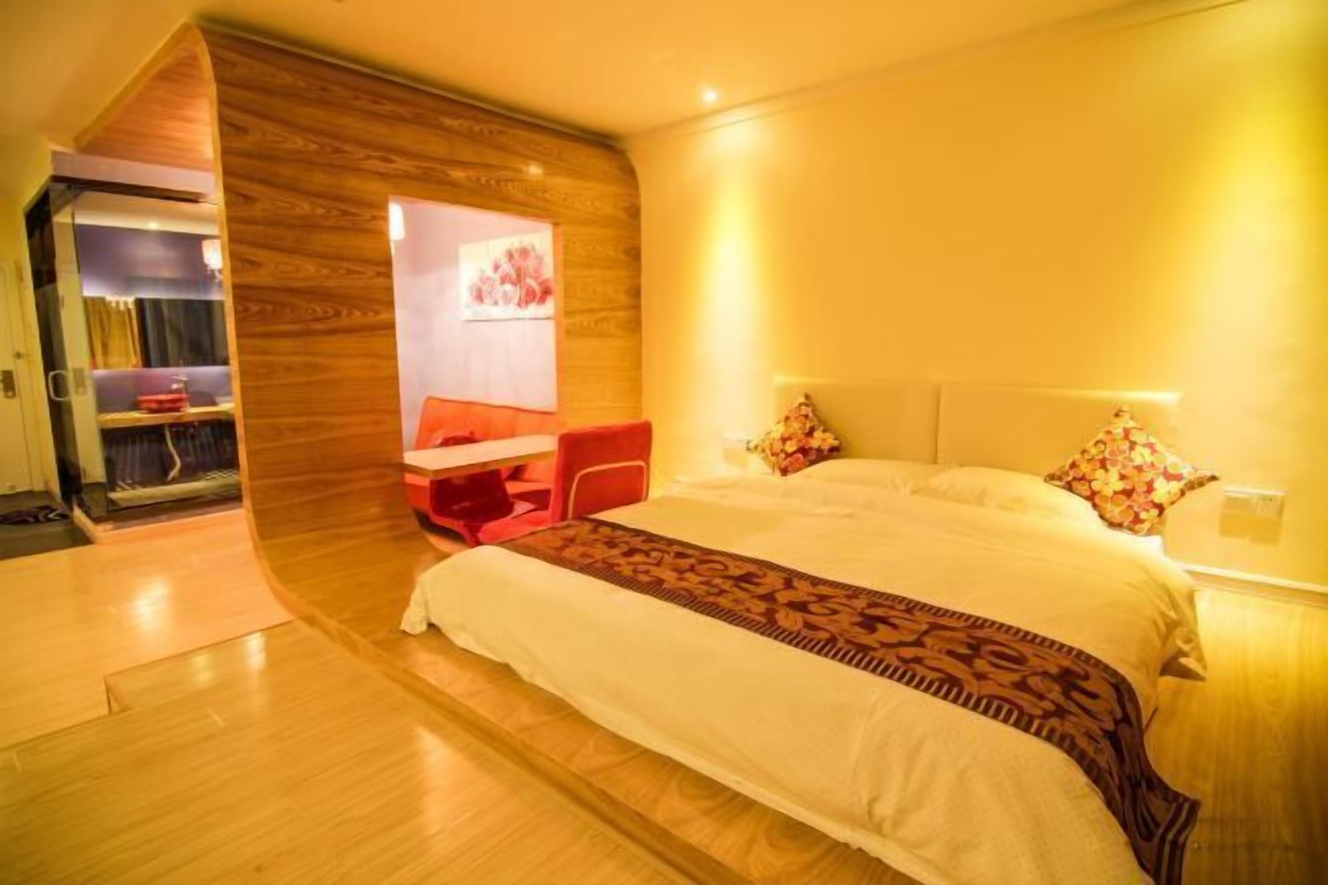 A modern bedroom with a large bed, a desk, and a wardrobe.