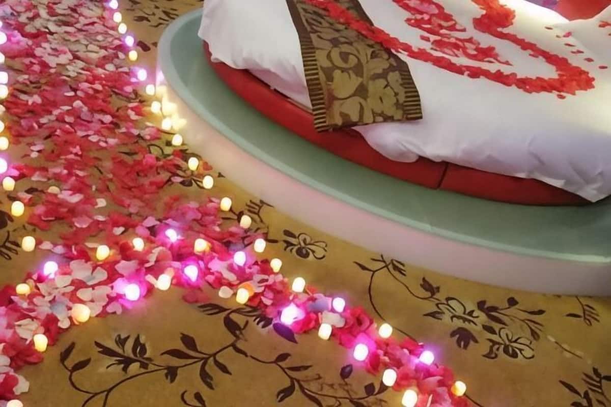 Ein Bett mit weißer und roter Bettwäsche, umgeben von einem Teppich mit floralem Muster und einem Zierkissen.