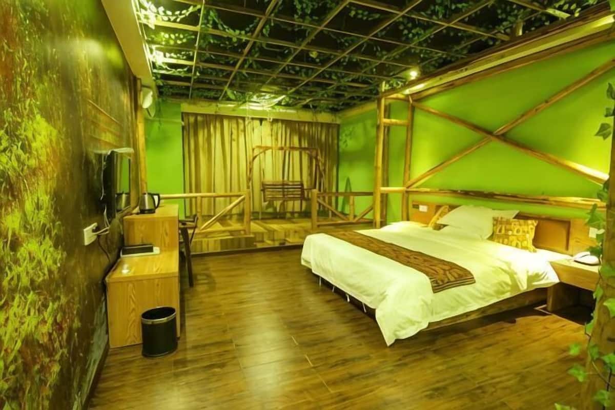 Quarto com cama, piso de madeira, televisão e cesto de lixo.