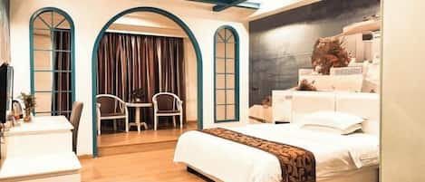 Habitación de hotel moderna con una cama grande, un escritorio y una silla. Hay dos ventanas arqueadas y una pared oscura con un elemento decorativo.