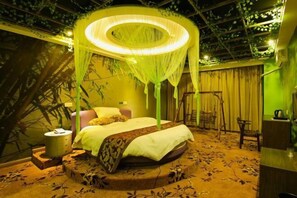A room with a bed, a bedside table, a chair, and a hanging light fixture.