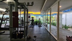 Una palestra con macchinari cardio, attrezzi per pesi e un'ampia vetrata che offre vista sul verde.