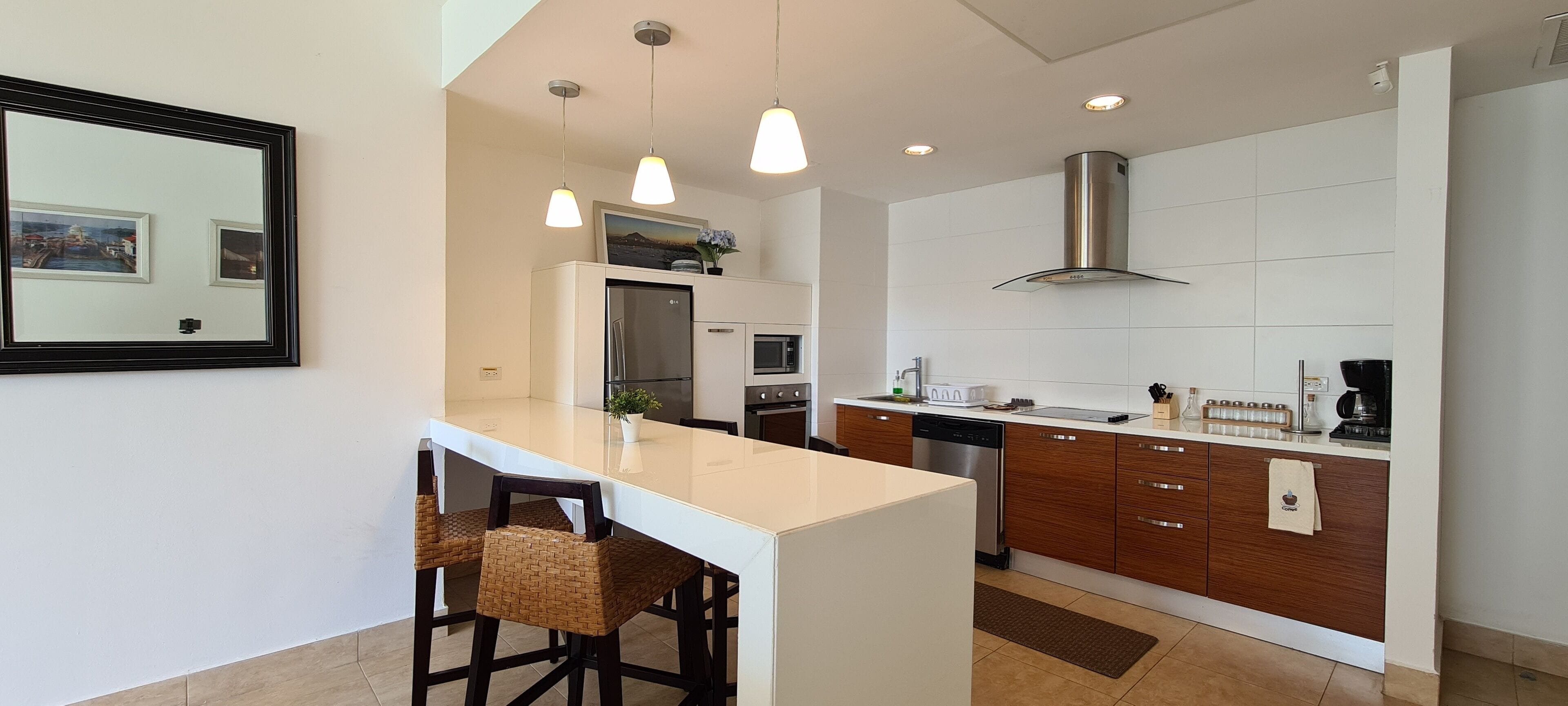 Een moderne keuken met een centraal eiland, barstoelen, een roestvrijstalen koelkast, een oven, een vaatwasser en een ruime afzuigkap.