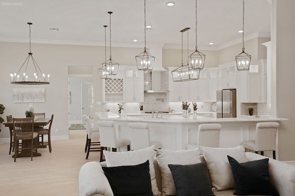 Una cocina moderna con armarios blancos, una isla central e iluminación colgante.