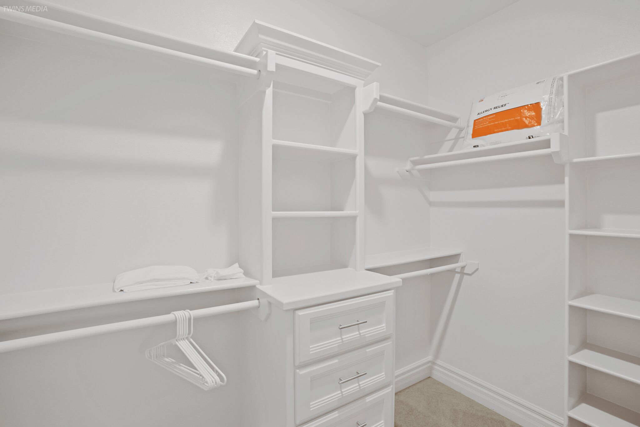 Ein weißer Kleiderschrank mit offenen Regalen, einer Kleiderstange und Schubladen.