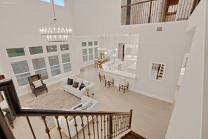 Amplio espacio habitable de varios niveles, con escalera, muebles blancos y una zona de cocina.