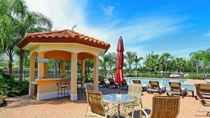 Un espace extérieur aménagé, abrité et doté d’une piscine, de chaises longues et d’un kiosque.