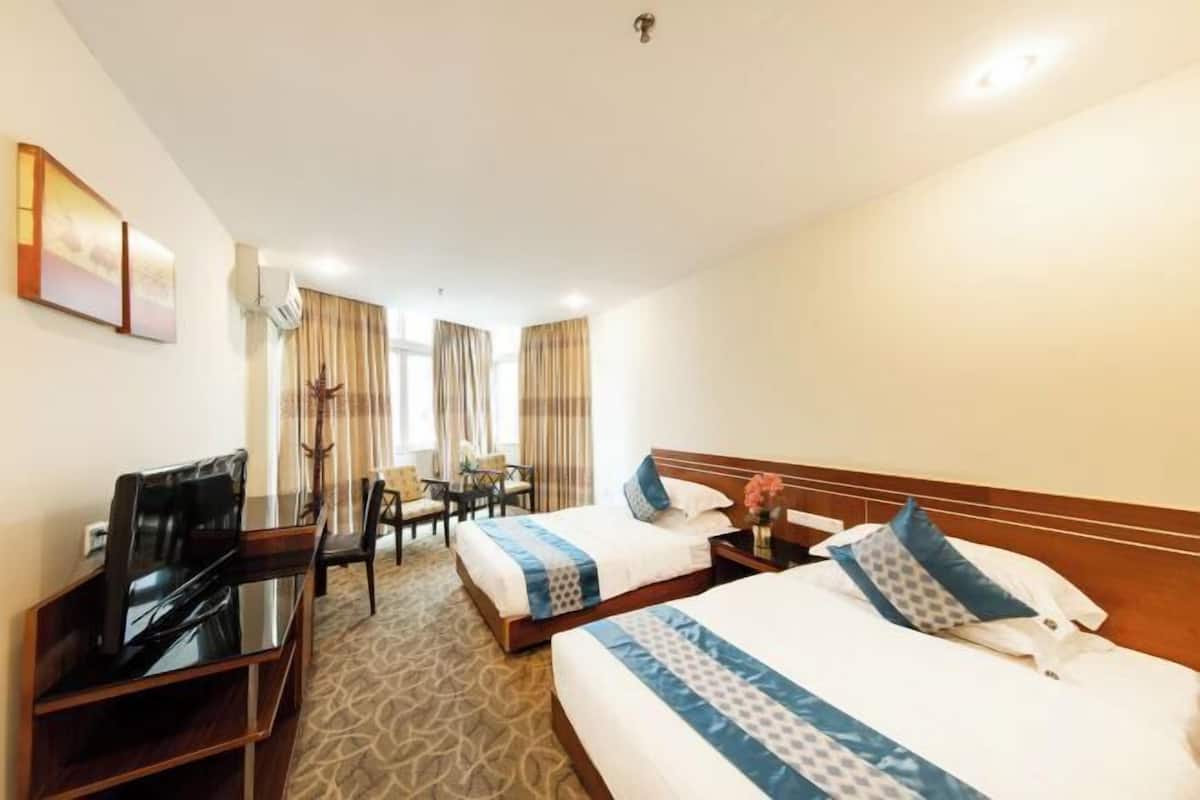 Una habitación de hotel con dos camas, un escritorio, una silla y un televisor.