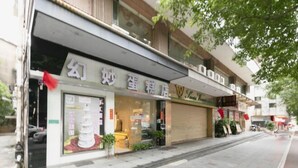 A storefront with a sign that reads 'Hua Mao Egg Shop' and a closed shutter on the right.