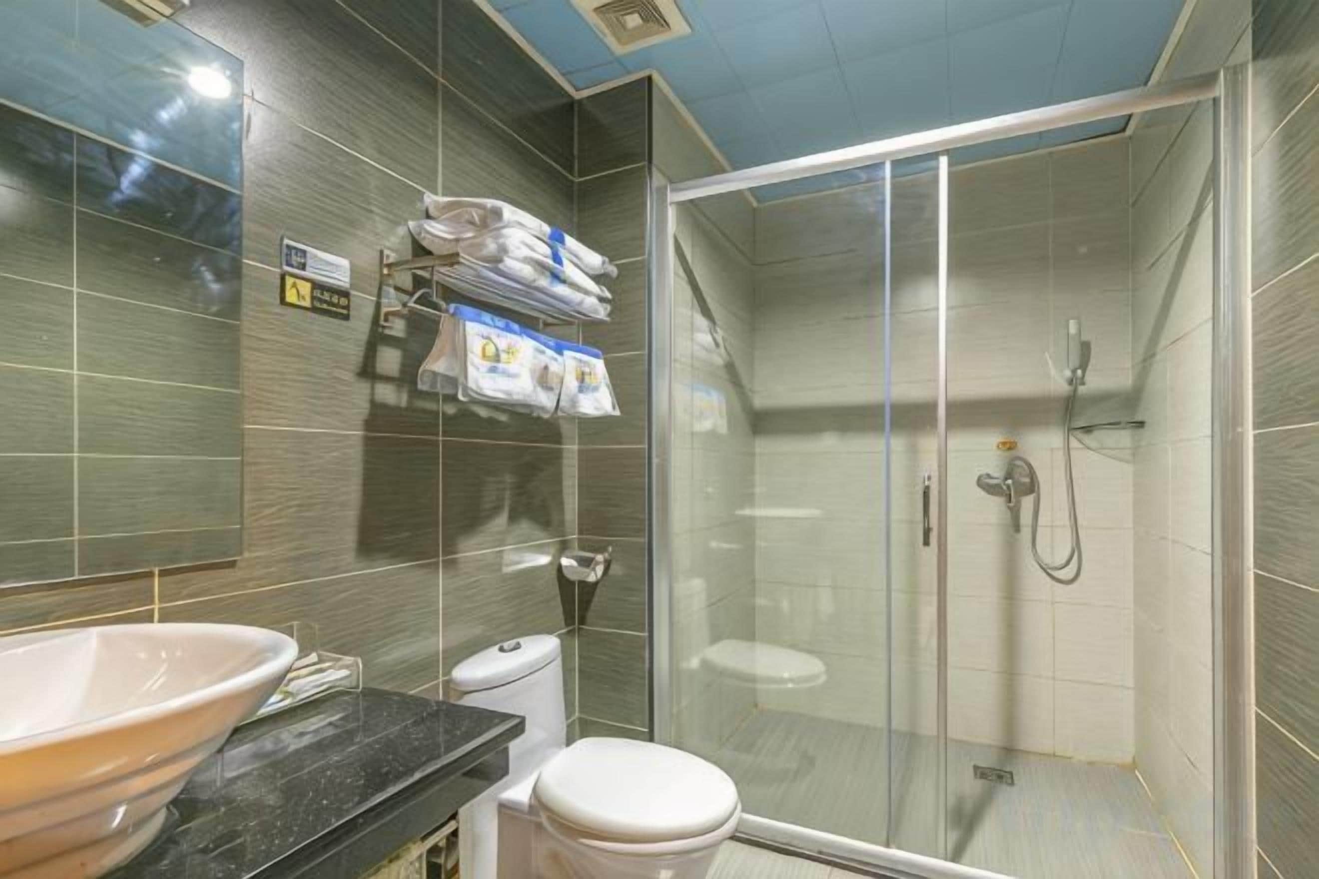 A bathroom with a glass-enclosed shower, a sink, and a toilet.