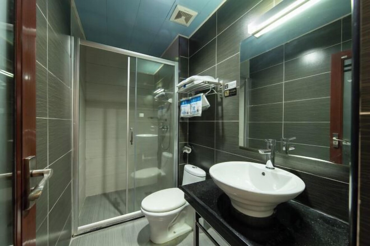 Ein modernes Badezimmer mit Duschkabine aus Glas, einer weißen Toilette und einem großzügigen Waschbecken in Weiß mit Spiegel darüber.