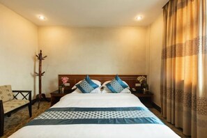 Una camera d'albergo con un letto, un comodino, una sedia e una finestra con tende.