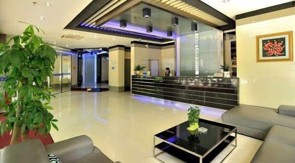Eine moderne Hotelhalle mit Rezeption, einer Sitzecke und einer großen Pflanze.