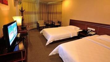 A hotel room with two beds, a desk with a TV, and a chair.