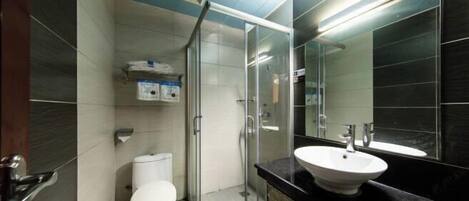 Un baño moderno con inodoro, cabina de ducha de vidrio, lavabo y un espejo grande.