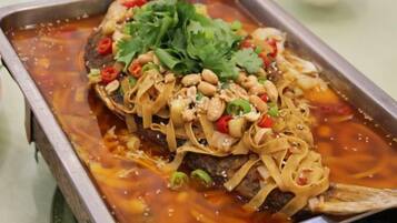 Un plat de poisson, servi sur un plateau et agrémenté de cacahuètes, de piment rouge et de coriandre.