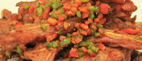 A plate of cooked meat with a garnish of diced vegetables.