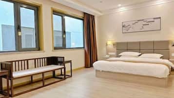 A hotel room with a bed, a bench, and large windows.