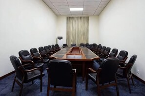 A conference room with a long table surrounded by chairs, a carpeted floor, and a curtain in the background. - Hancun River Villa (Beijing)