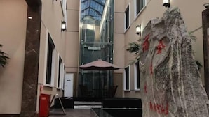 A hotel lobby with a glass atrium, a rock sculpture, and a reception desk. - Hancun River Villa (Beijing)