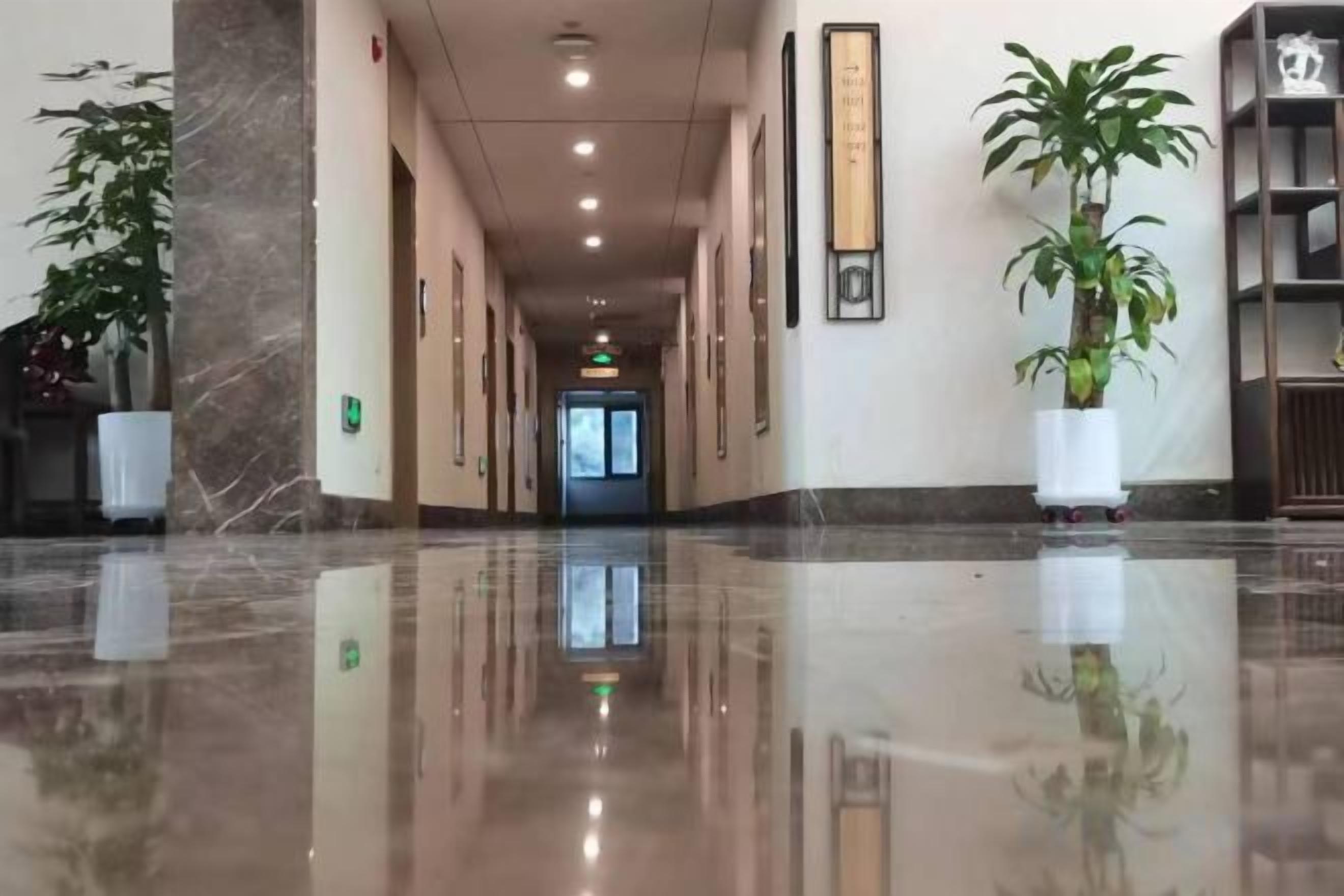 A polished lobby with a marble floor, potted plants, and framed artwork on the walls.