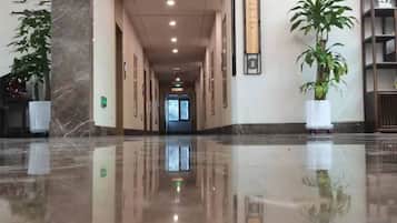 A polished lobby with a marble floor, potted plants, and framed artwork on the walls.