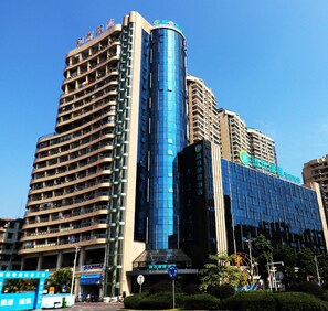 A multi-story hotel with a prominent curved glass facade, multiple balconies, and signage indicating amenities such as a city center location and a restaurant. - City Comfort Inn (Qingyuan)