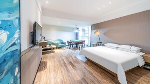 Ett modernt hotellrum med en stor säng, ett skrivbord, en soffa och ett matbord.
