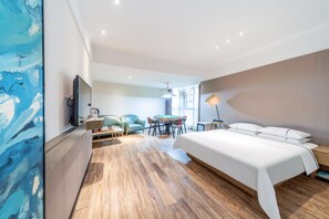 A modern hotel room with a large bed, a desk, a sofa, and a dining table. - City Comfort Inn (Qingyuan)
