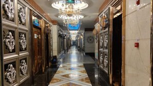 Un long couloir élégant, doté d’un sol à motifs, de portes richement décorées et d’un grand lustre.