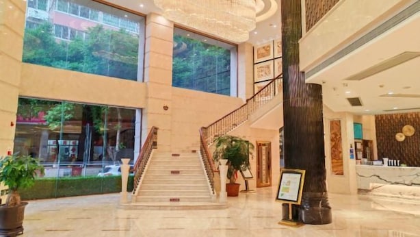 Un hall d’entrée spacieux, agrémenté d’un grand escalier, de grandes fenêtres et d’un lustre.